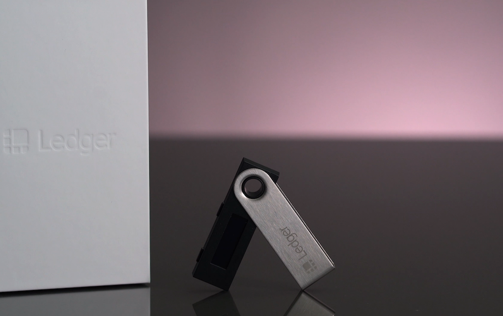 Ledger Nano S cryptocurrency hardware wallet on display against a gradient background