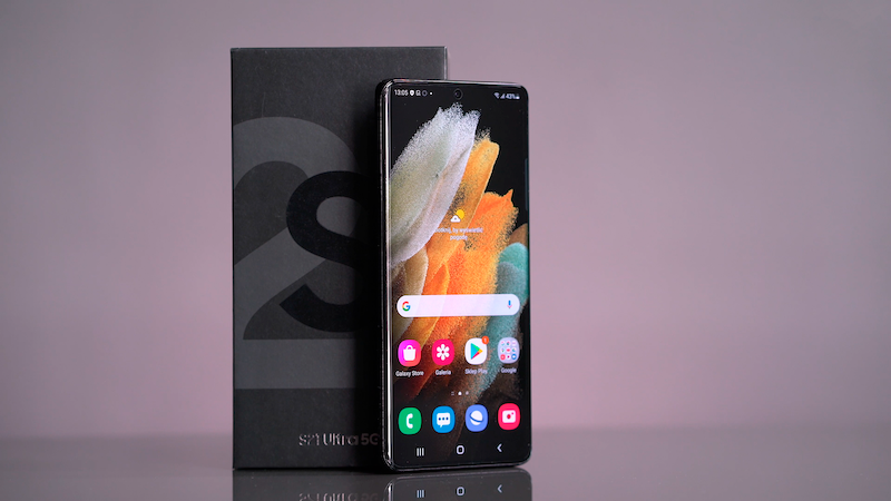 Samsung Galaxy S21 Ultra 5G smartphone displayed next to its box on a pink background.
