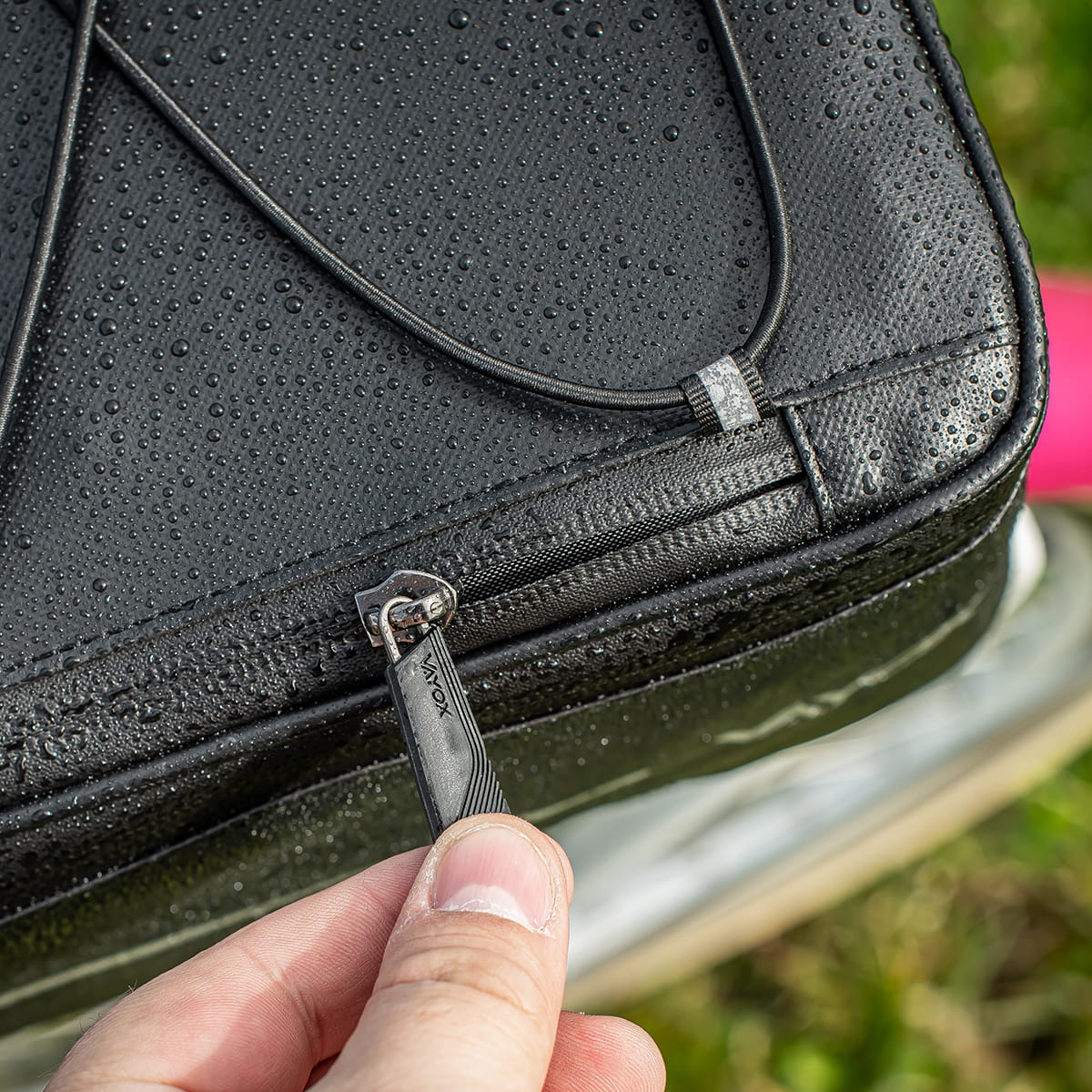 Close-up of Vayox VA0166 black bike bag zipper on wet surface, designed for rear rack, 8L capacity, waterproof material.