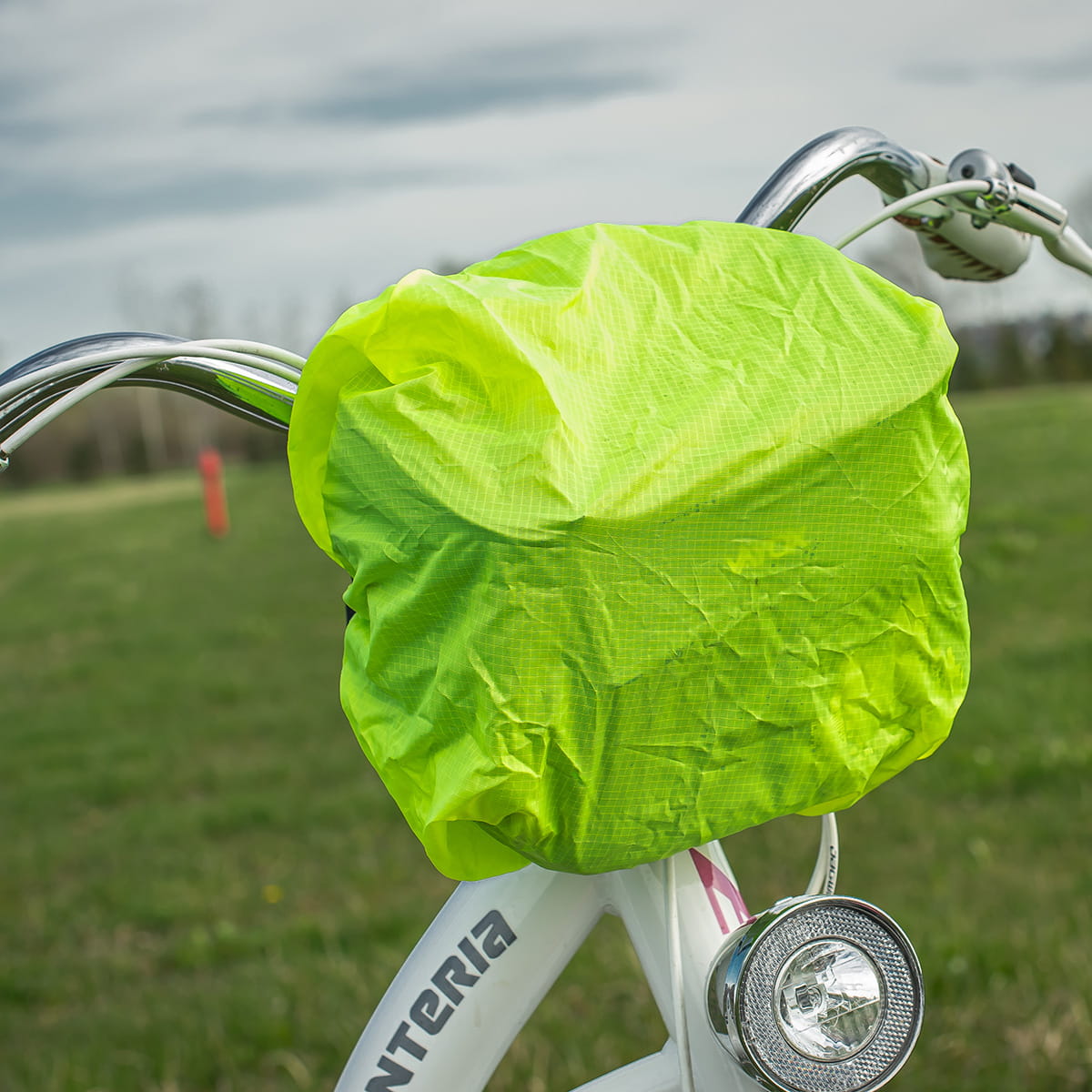 Neon green bike handlebar bag cover on a white bicycle outdoors