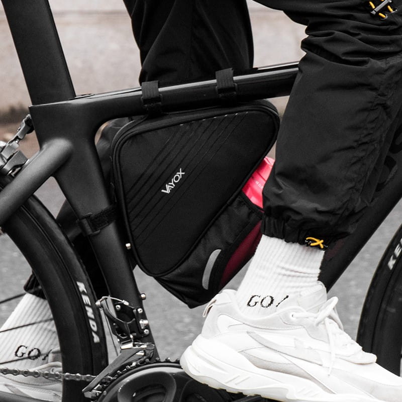 Person cycling with Vayox VA0348 frame bag and bottle holder, 1.5L capacity, sleek design for convenient storage on bike frame.