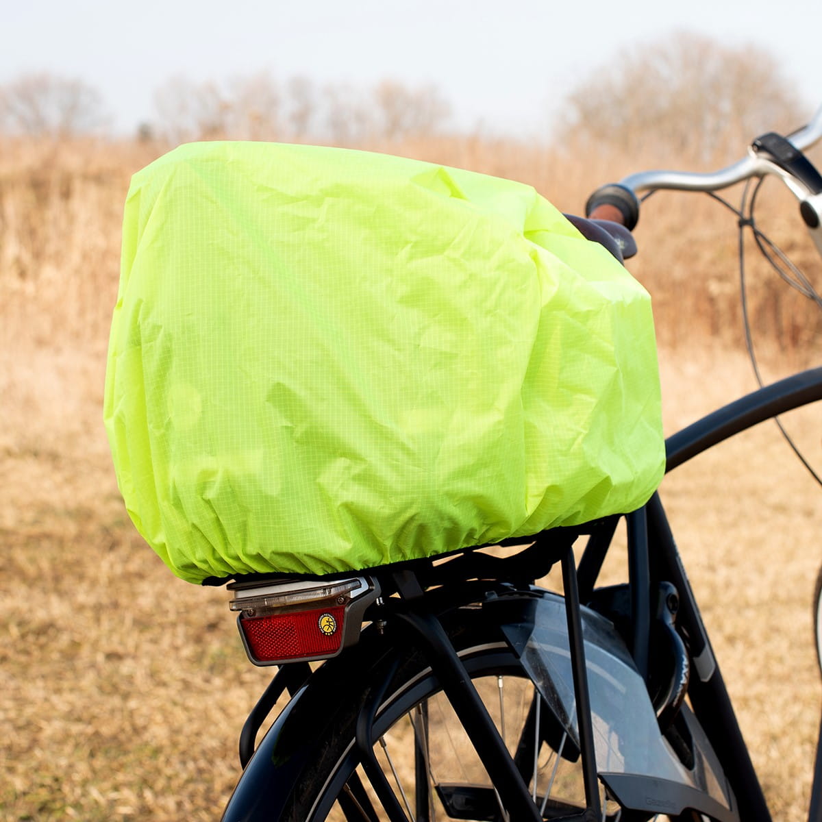 Waterproof neon yellow cover on Vayox VA0346 bike pannier for rear rack, outdoor setting.