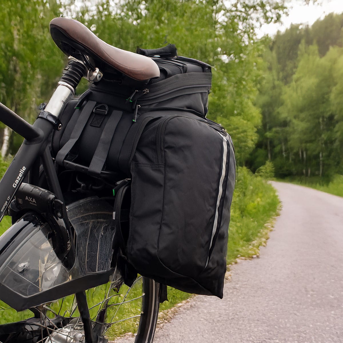 Fahrradtasche Vayox VA0346 35L in Schwarz am Fahrradträger, ideal für längere Touren, geräumig und robust, auf einer ländlichen Straße.
