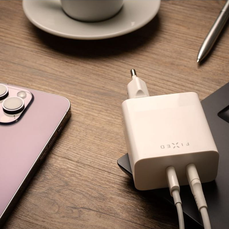 Ladegerät 2x USB-C, 65W PD Fixed Dual Port Charger in Weiß auf Holz-Tisch, neben Smartphone und Kaffeetasse, zum gleichzeitigen Aufladen geeignet.