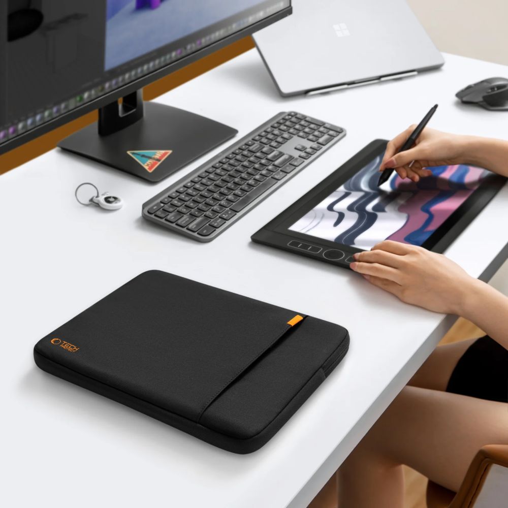 Schwarz Tech-Protect Defender Laptoptasche auf einem Schreibtisch neben einem Laptop und Grafiktablet.